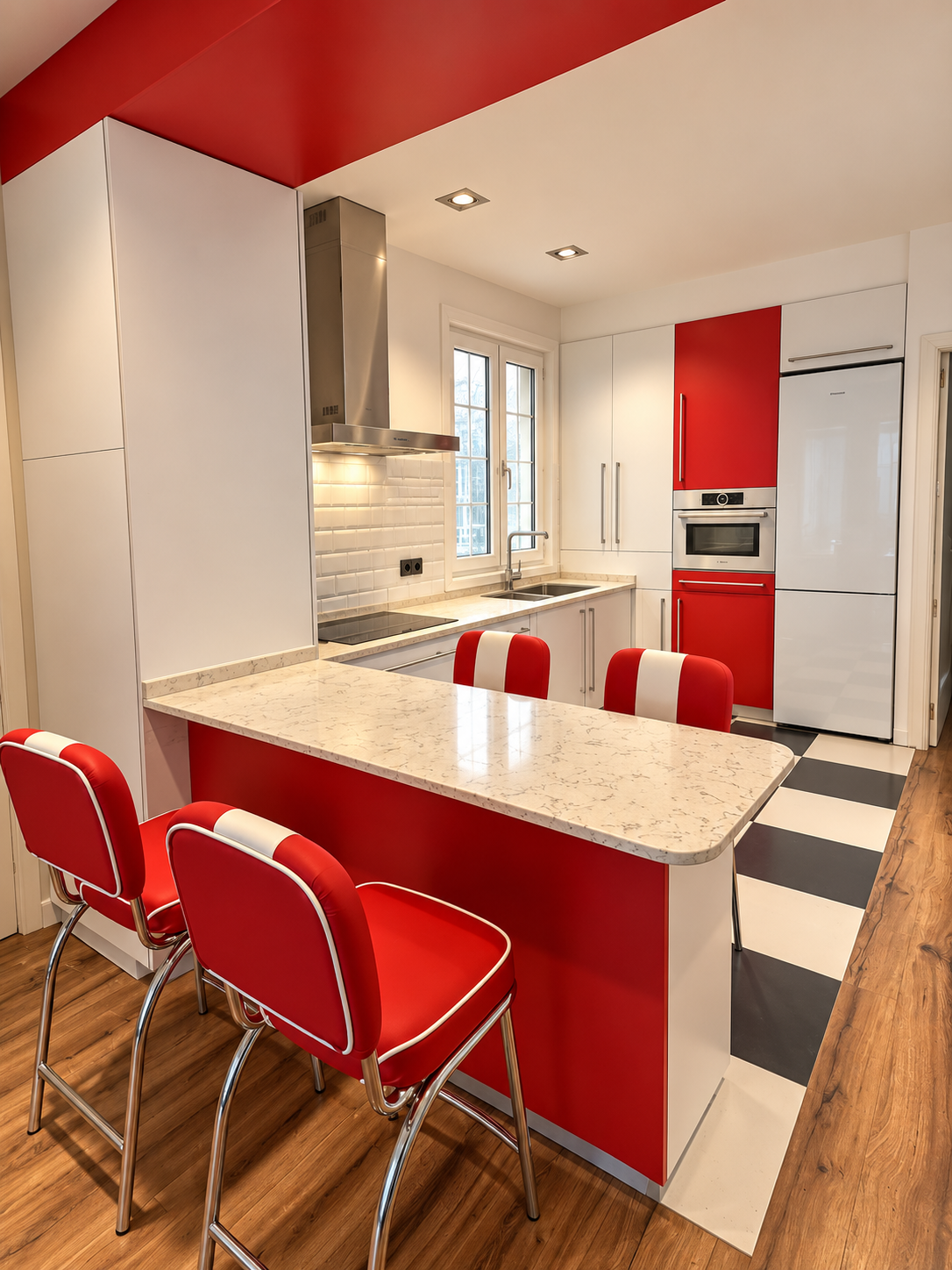 Vista de la cocina del proyecto Alcalá 175 con barra de madera, frentes rojos y mobiliario blanco